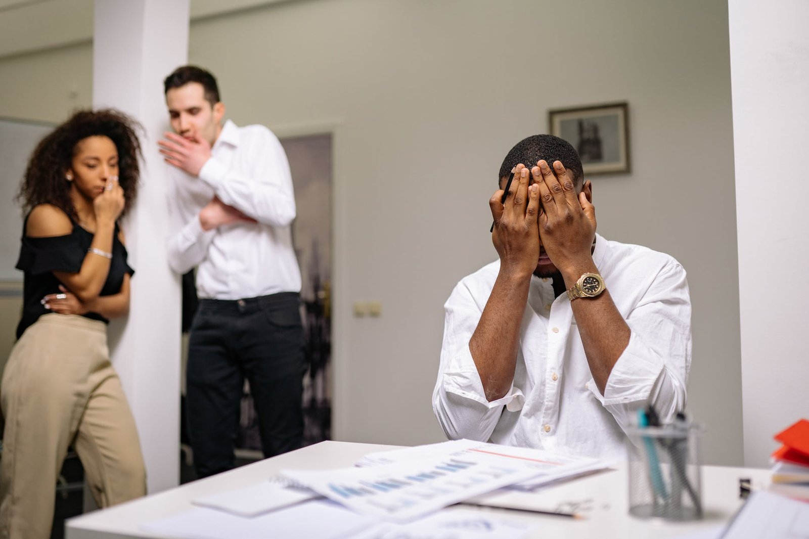 man in white dress shirt covering his face